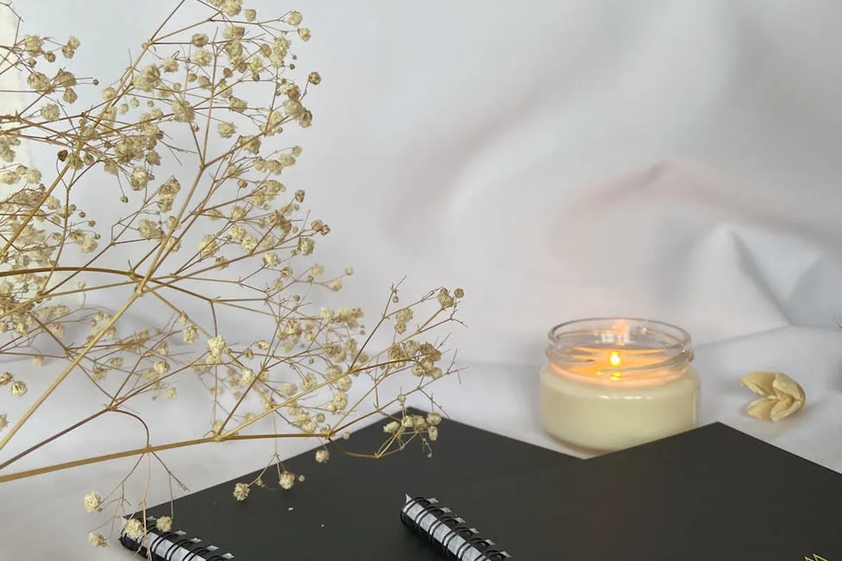 Smiling woman with a towel wrapped around her head, applying foamy face wash in a bathroom.