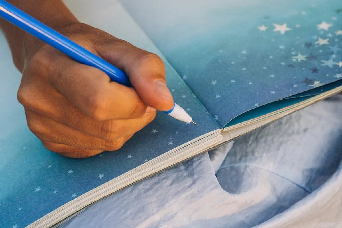 Smiling woman with a towel wrapped around her head, applying foamy face wash in a bathroom.