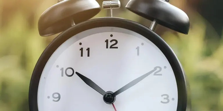 Analog alarm clock with two bells showing approximately 10:10.