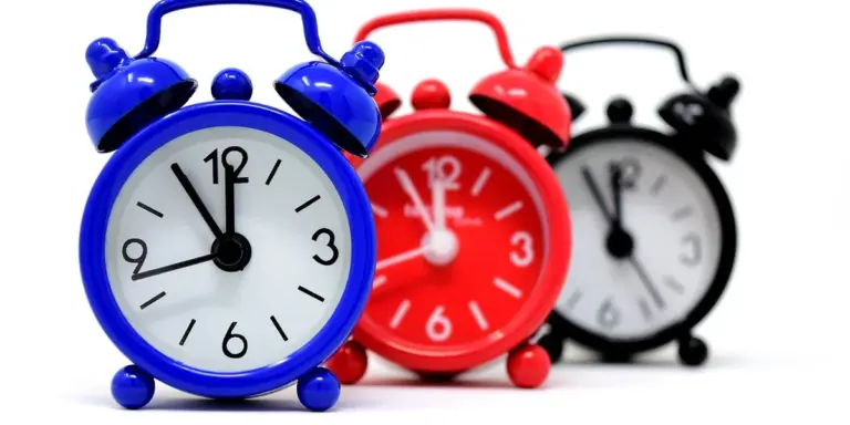 Three alarm clocks in blue, red, and black on a white background.