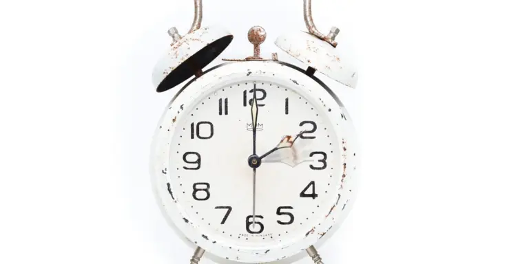 White vintage alarm clock with rust spots and twin bells on top