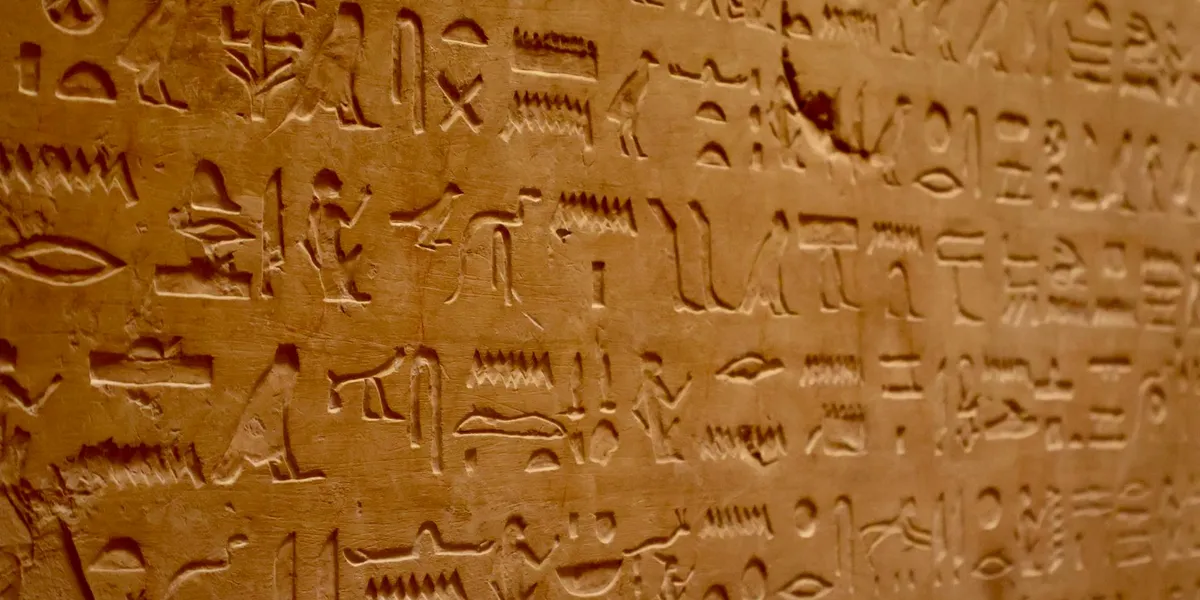 Close-up of weathered Egyptian hieroglyphs carved into a stone wall, suggesting dream-symbol meanings and ancient beliefs.