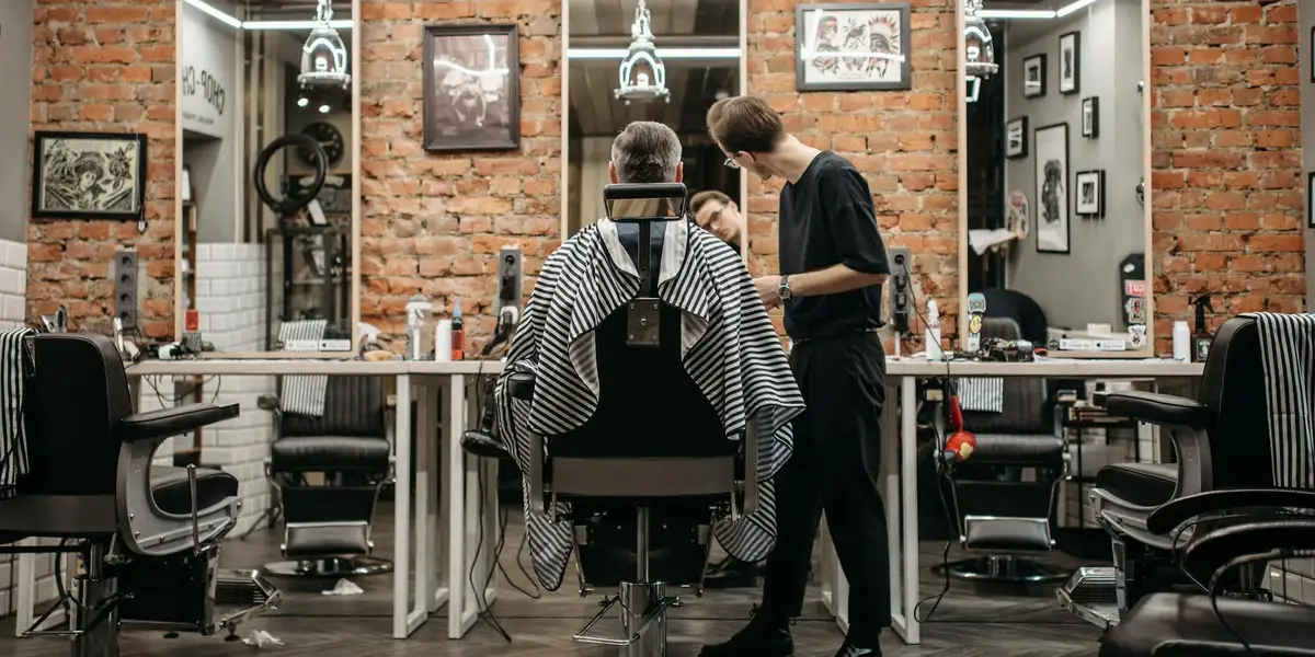 Barber trimming a customer's hair in a brick-walled barber shop with vintage decor and mirrors