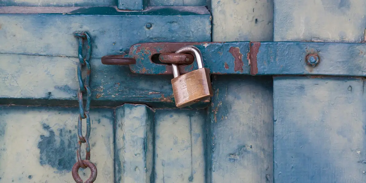 Blue wooden door secured with a padlock and chain, symbolizing being blocked or restrained