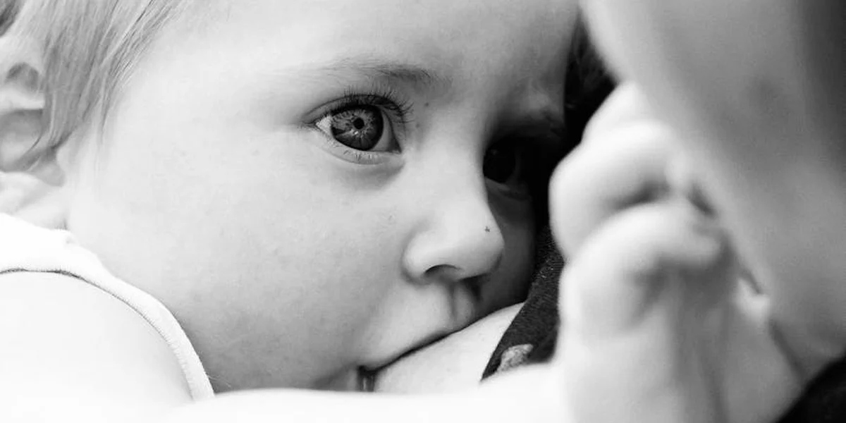 Close-up of a baby breastfeeding in grayscale.