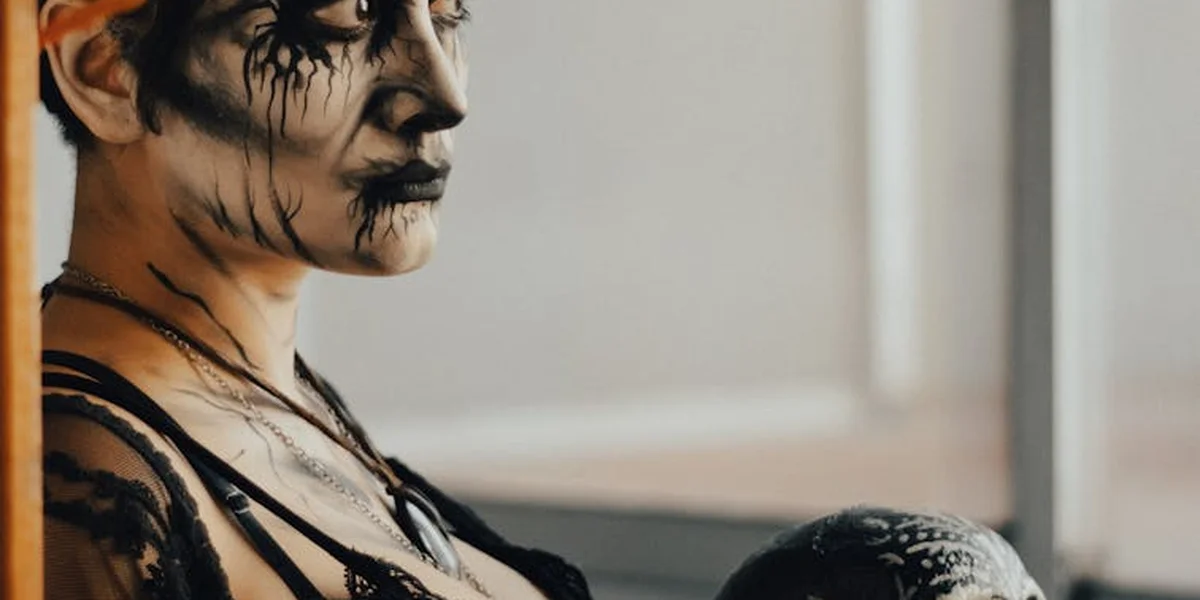 A person with black, skeletal-style face paint gazes to the left, embodying ritual transformation.