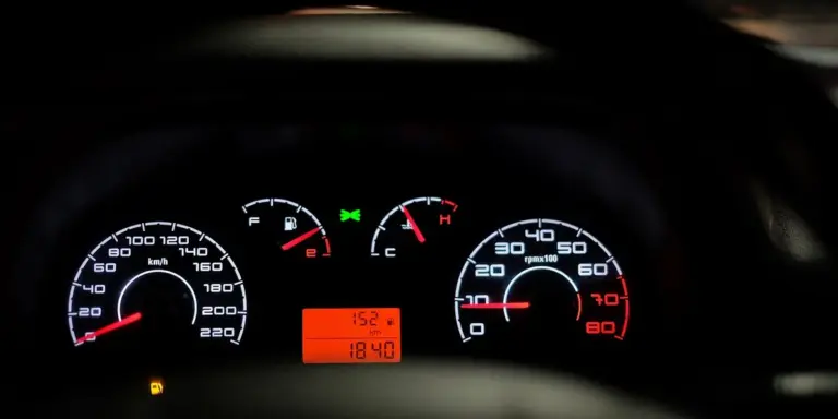 Close-up of a car dashboard with illuminated speedometer and gauges.