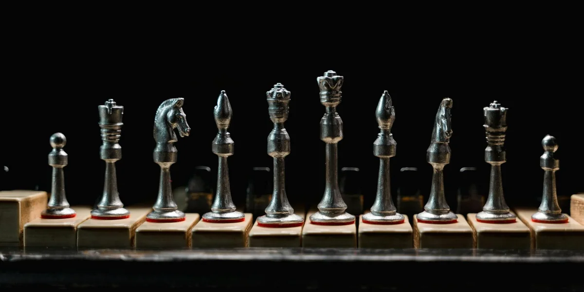 Row of chess pieces lined up on a wooden board against a black background, suggesting strategic choices and unknown meanings in dreams.