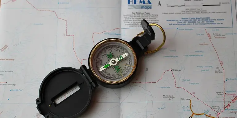 A brass compass lies open on a light-colored map, suggesting navigation, direction, and inner exploration within dream imagery.