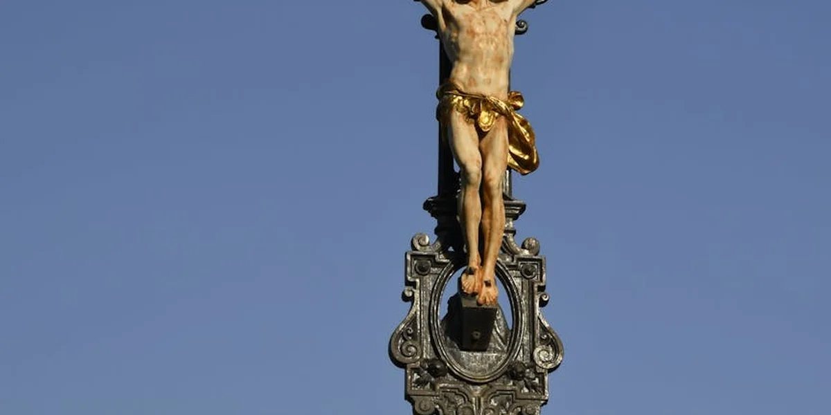 Crucifix statue of Jesus on the cross against a clear blue sky