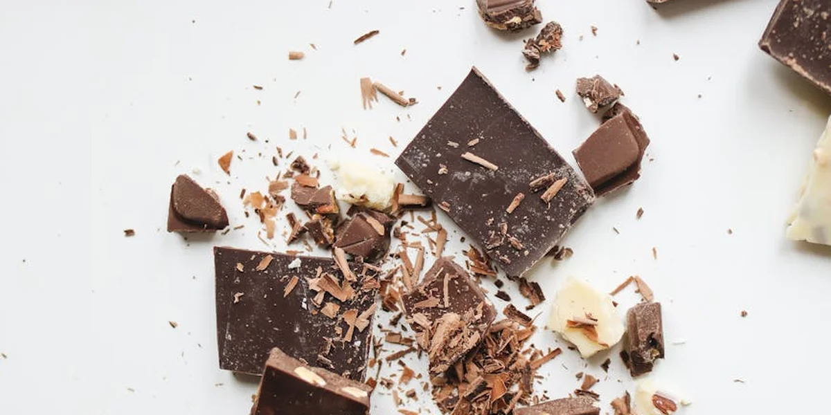 Close-up of scattered pieces of dark and milk chocolate on a white surface