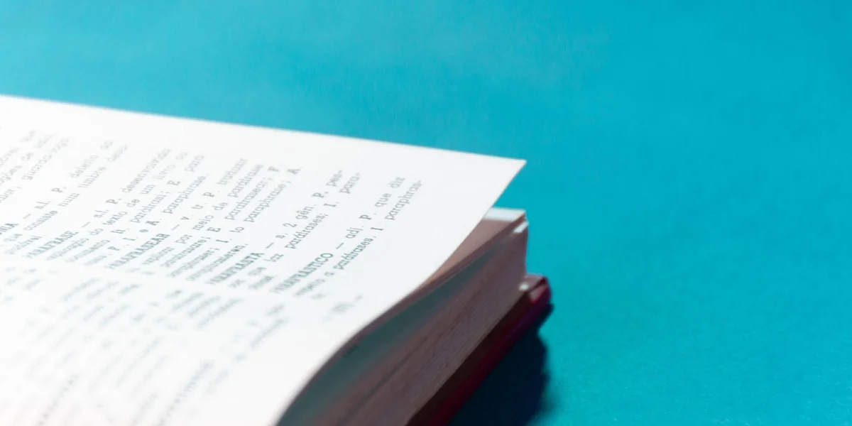 Close-up of an open book with printed text on a bright blue surface, representing dream dictionary resources.
