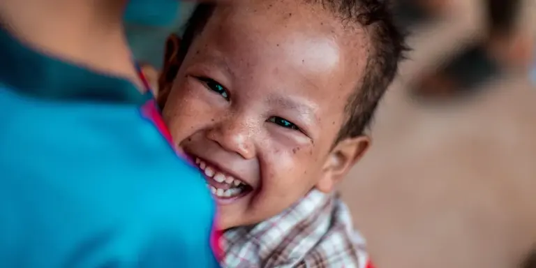 A smiling child being hugged, radiating warmth and connection