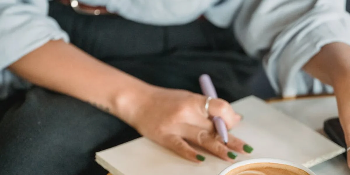 Close-up of hands writing in a notebook with a purple pen
