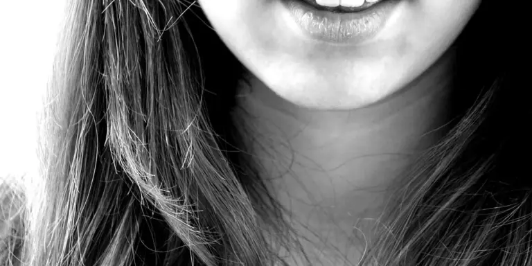 Close-up black-and-white photo of a smiling mouth showing teeth.