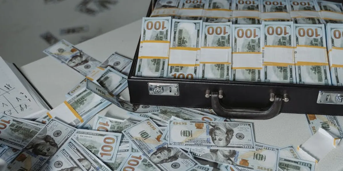 A briefcase full of US $100 bills with more cash scattered around, illustrating wealth and stewardship themes for biblical dream interpretation.