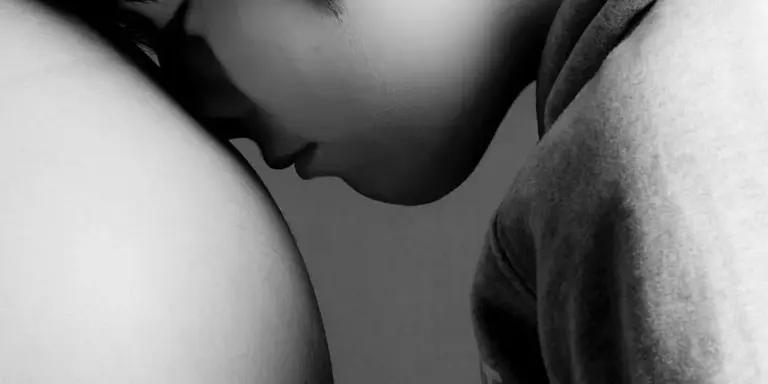 Black-and-white close-up of a person resting their head on another person's shoulder