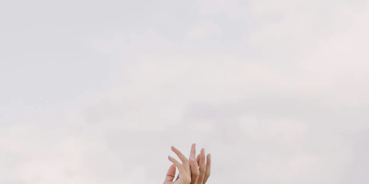 A pair of hands interlaced against a soft, light background, illustrating overlapping symbols in a dream wheel.
