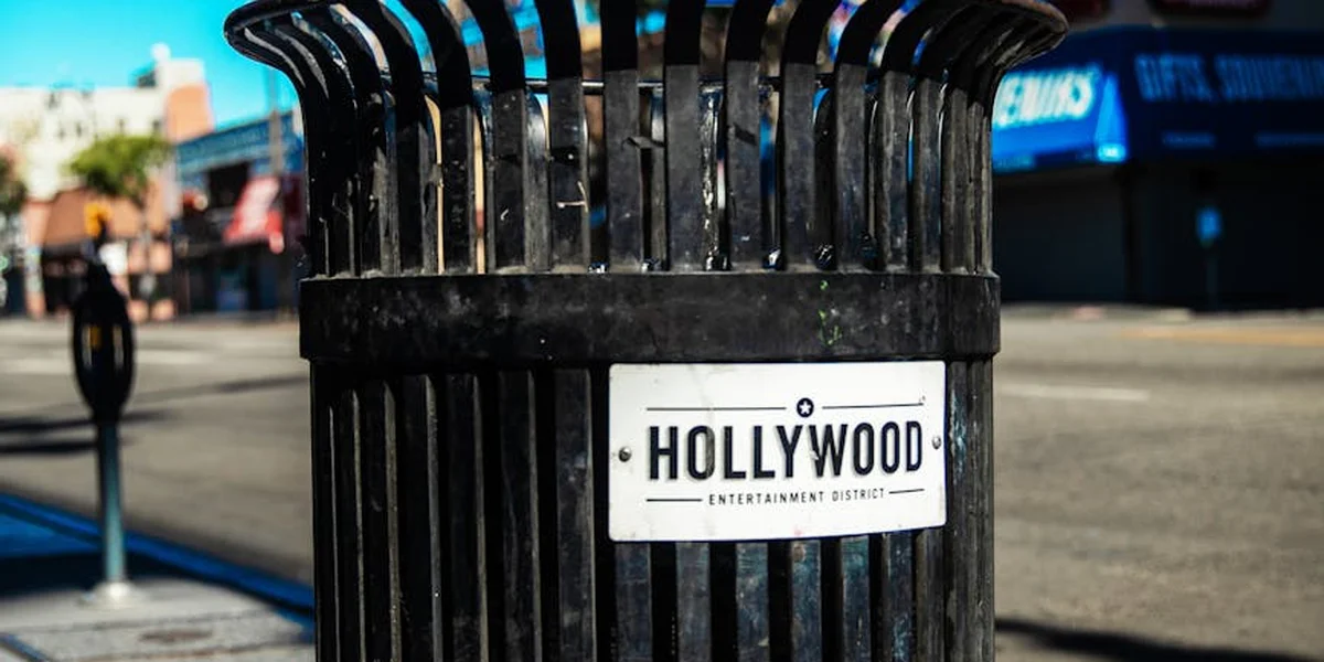 Outdoor street scene featuring a black public trash can with a Hollywood label, symbolizing letting go of dream trash and embracing real-life cleansing.