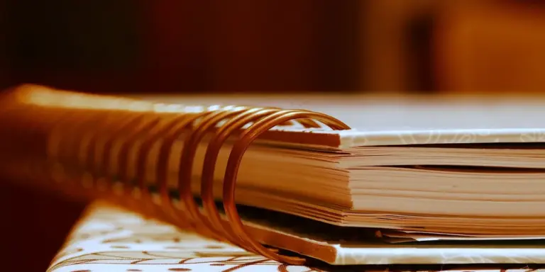 Close-up of a spiral-bound notebook on a warm-lit desk, ready for dream journaling.