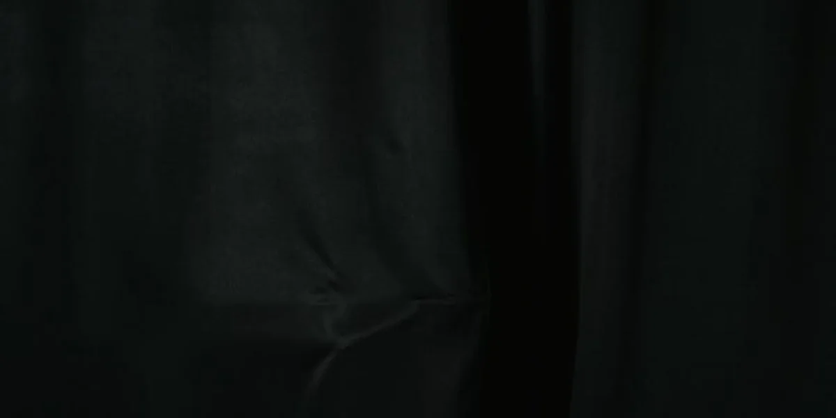 Dark theater curtains with a slim strip of light suggesting anticipation and the tension of an upcoming performance.