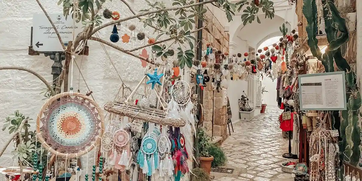 Colorful dreamcatchers and handmade crafts hanging in a sunlit market alley, suggesting the everyday symbols found in spiritual dreams.