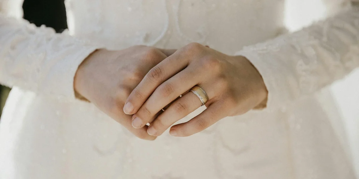 Close-up of intertwined hands wearing wedding rings, symbolizing unity and commitment in marriage dreams.