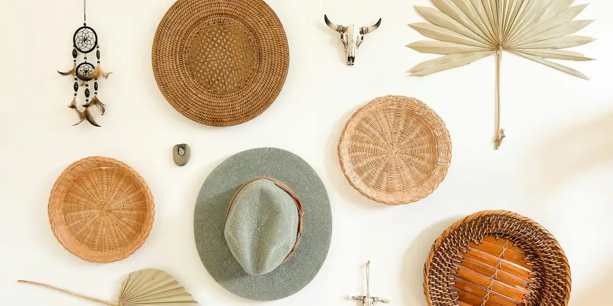 A wall decorated with woven baskets, hats, a dreamcatcher, and dried palm leaves, evoking natural textures and calm.