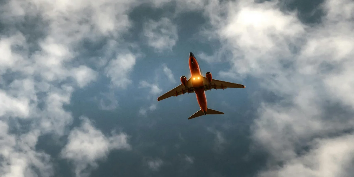 Airplane flying overhead in a blue sky dotted with white clouds.