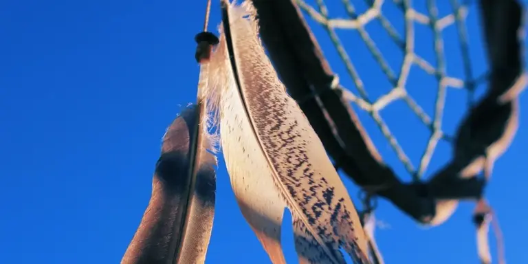 Close-up of a dreamcatcher with a blue-toned net against a clear blue sky, highlighting the color blue in dream imagery.