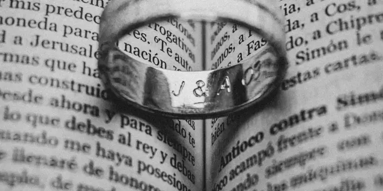 Close-up of a wedding ring resting on a page with printed text.