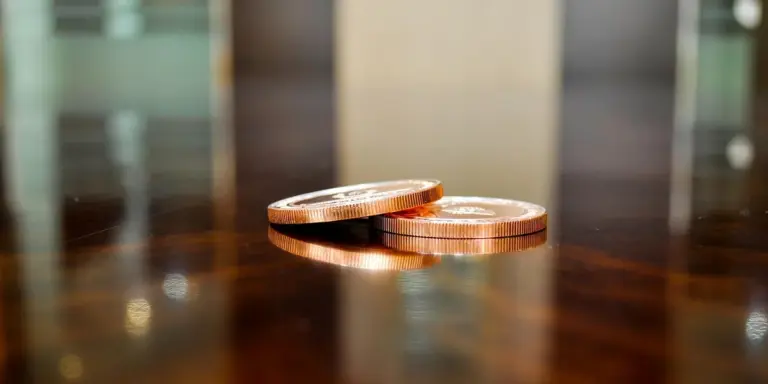 Close-up of copper coins on a wooden surface, symbolizing money.