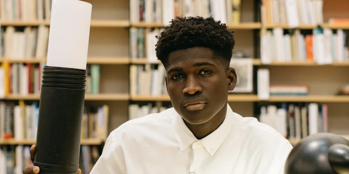 A thoughtful student stands in a library, surrounded by books, embodying the process of turning dreams into actionable plans.