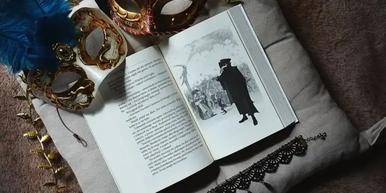 An open book lies on a cushioned surface, surrounded by ornate masquerade masks, blue feathers, and delicate lace, suggesting concealment and mystery in dreams.
