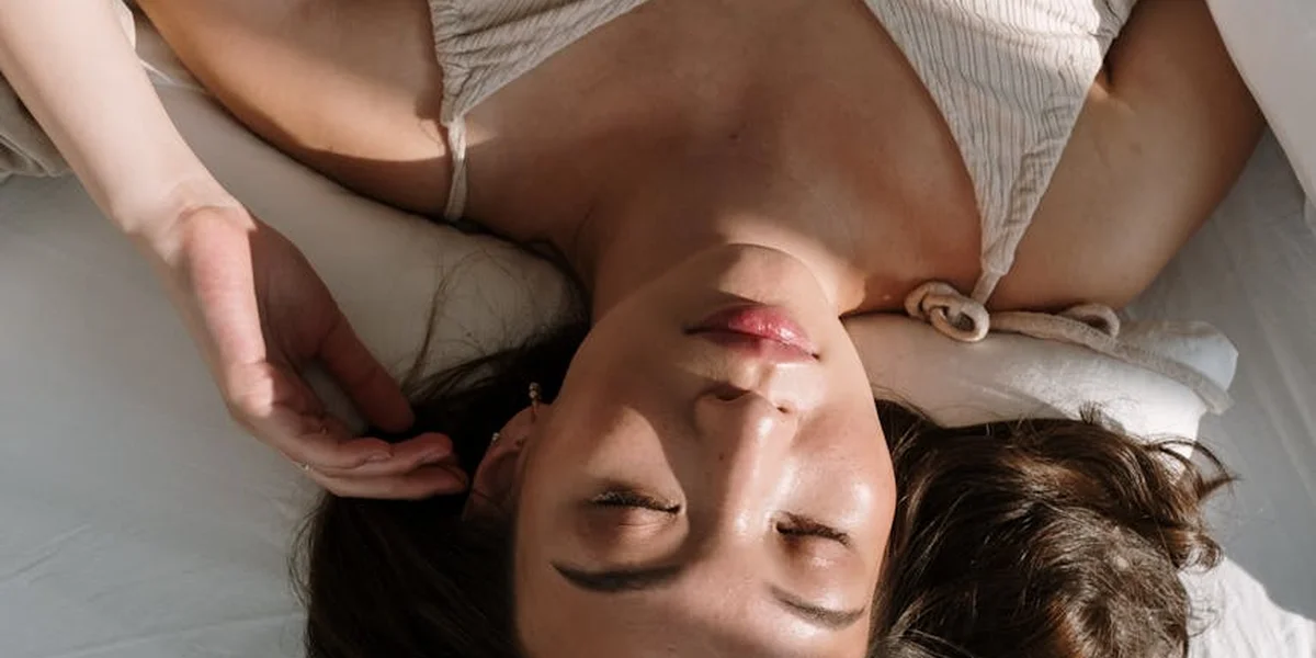 Close-up of a person with eyes closed, resting on a bed, conveying calm sleep and dream-like imagery.