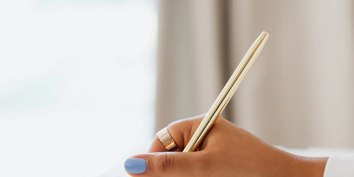 Close-up of a hand holding a pen, poised to write.