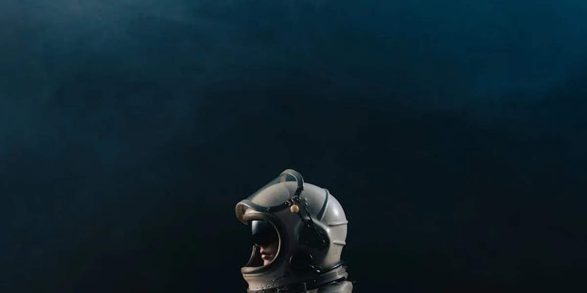A metallic diving helmet floats in a deep blue, dreamlike void, symbolizing a journey into the subconscious.