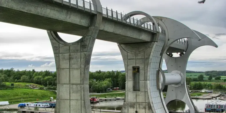 Concrete elevated structure with curved metal arches over a rural green landscape.