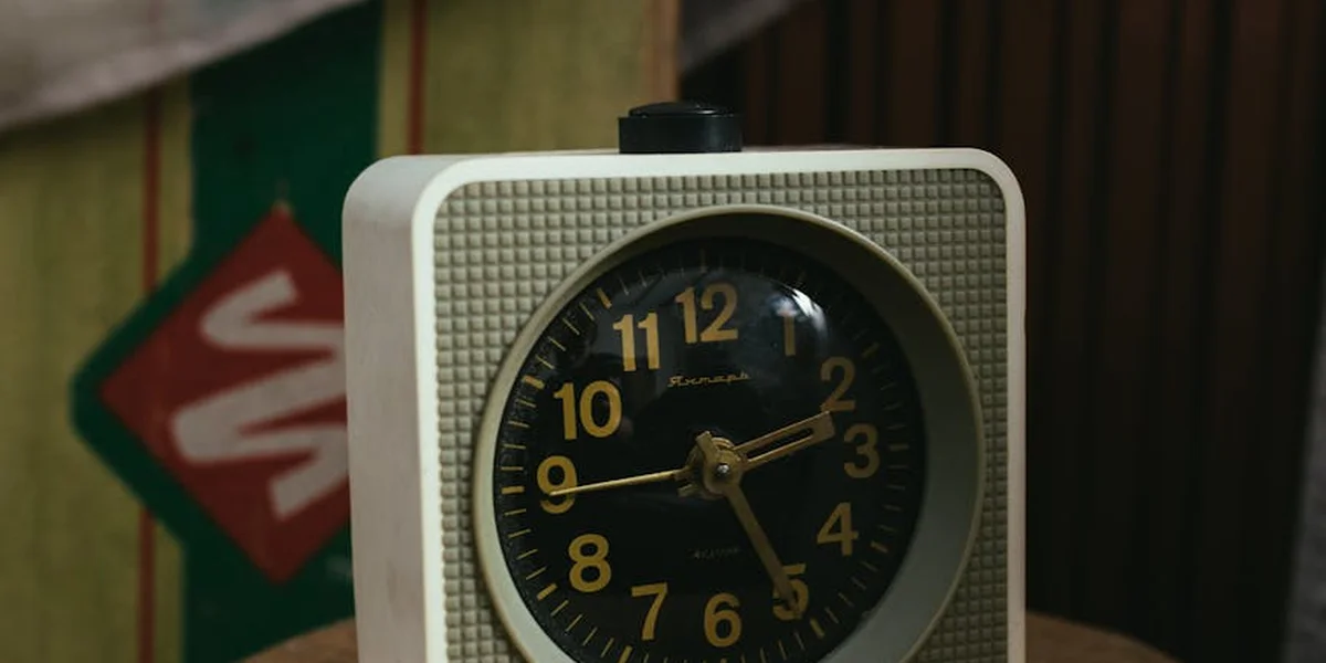 Close-up of a vintage analog alarm clock with gold numbers, set against a blurred, dreamlike background.