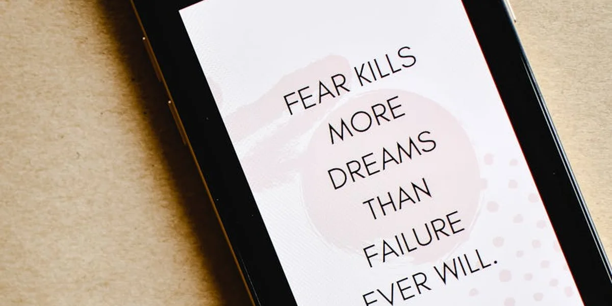 Phone screen showing a card that reads 'FEAR KILLS MORE DREAMS THAN FAILURE EVER WILL.'
