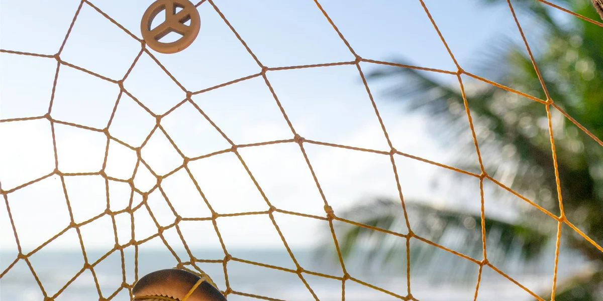 Close-up of a warm-toned, web-like net against a bright blue sky, with blurred palm leaves in the background, suggesting interconnected meanings beyond food.
