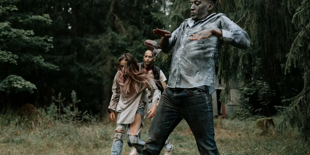 People running through a dim forest, appearing frightened as if being chased.