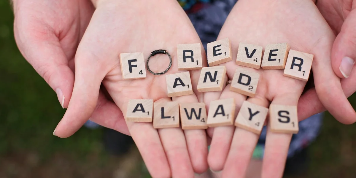 Close-up of cupped hands holding Scrabble tiles that spell 'FOREVER AND ALWAYS', symbolizing giving and enduring outreach.