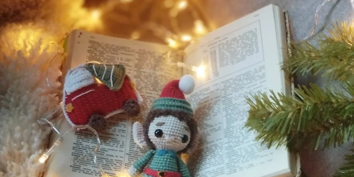 Two handmade knitted dolls sit beside an open book with warm fairy lights and pine branches, creating a cozy, beginner-friendly scene for dream analysis.