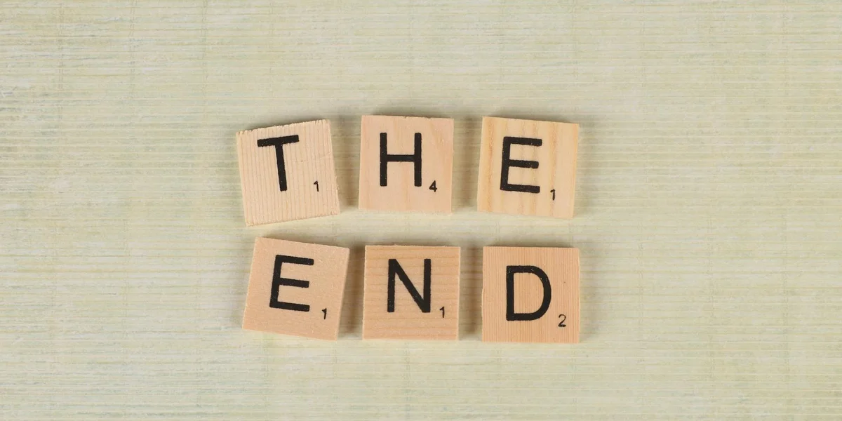 Wooden Scrabble-style tiles spell 'THE END' on a light, textured surface.
