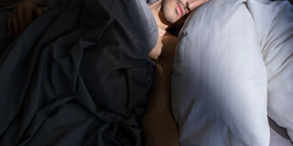 A person resting quietly in bed under cozy blankets, illustrating a calm, restful sleep environment.