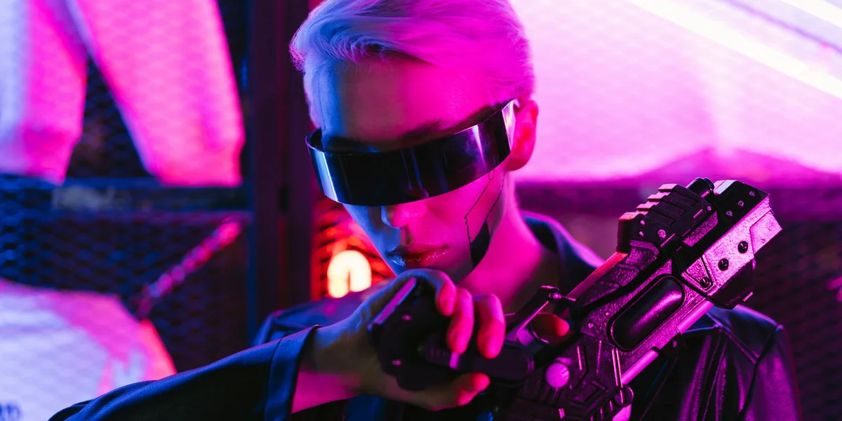 A person wearing a futuristic visor in a neon-lit space, gripping a handgun, suggesting a moment of inner tension and transformation.