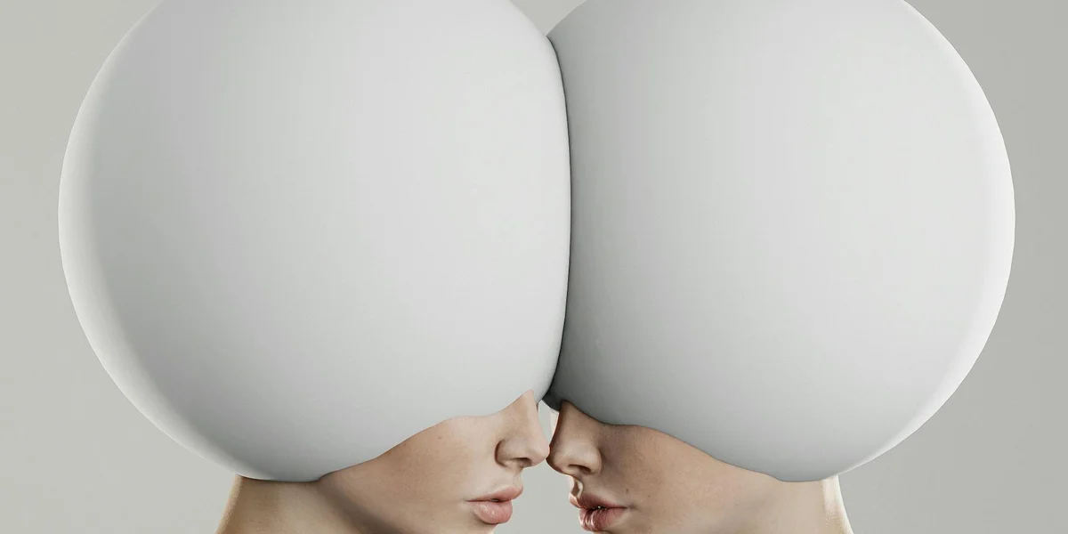 Close-up of two people kissing, their heads forming oversized rounded shapes in a surreal, abstract image.