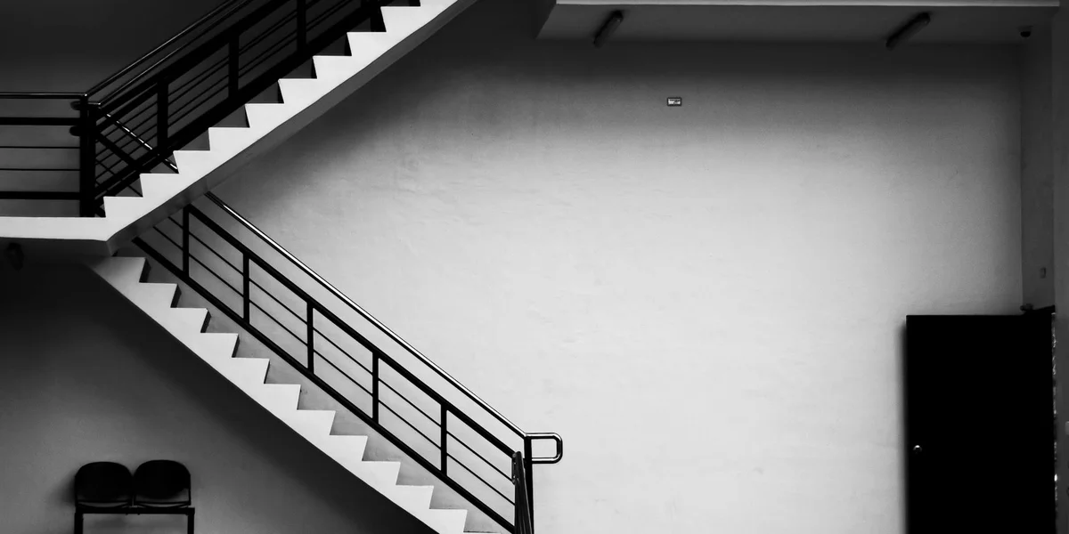 Black-and-white interior stairwell with intersecting flights forming impossible geometric angles.