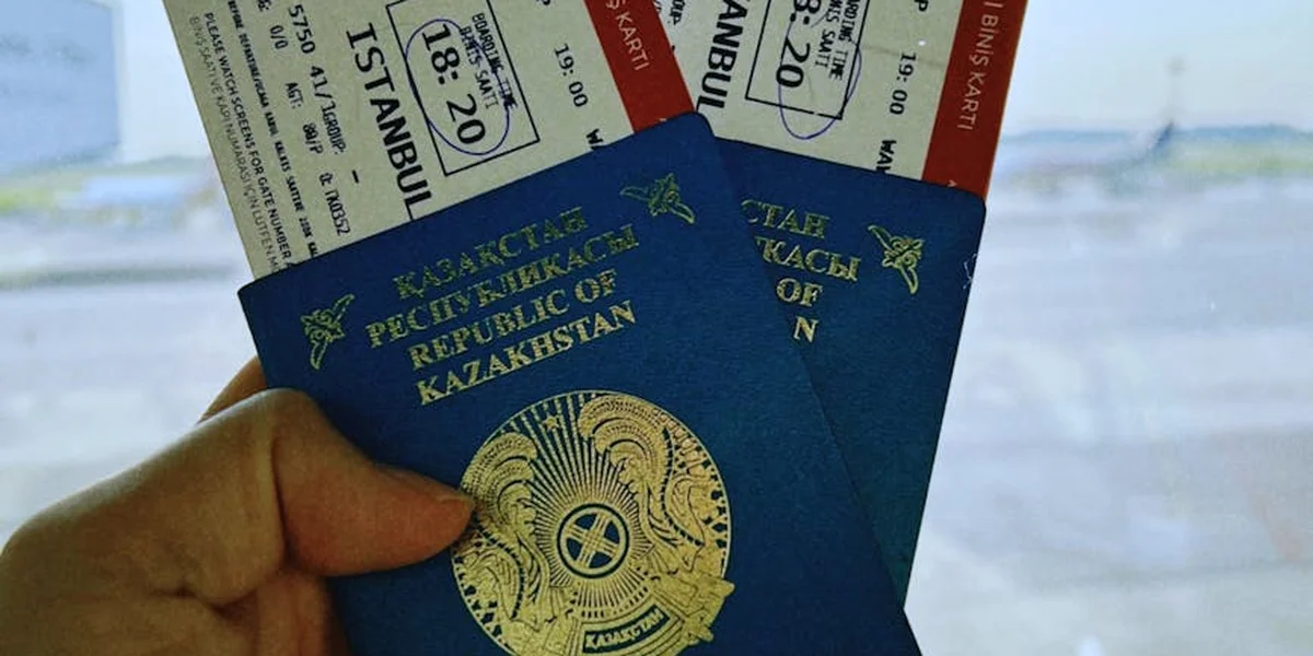 A person holding blue Kazakhstan passports with travel tickets and boarding passes in the background, symbolizing navigating a foreign country without speaking the language.